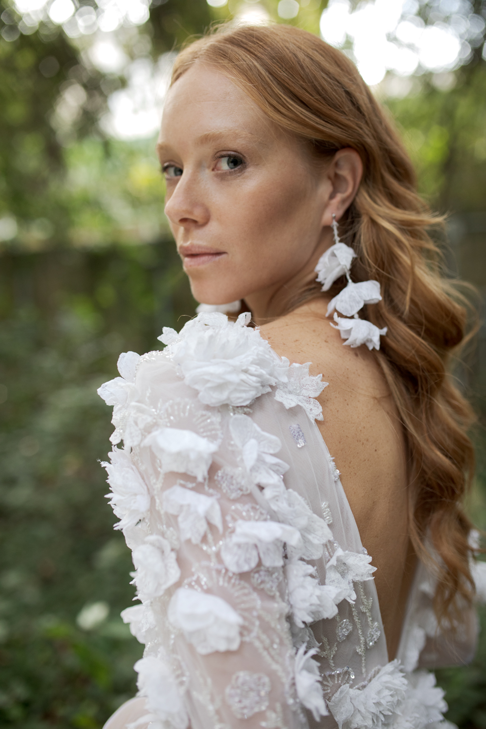 Ritratto all’aperto di una sposa con capelli raccolti e orecchini floreali bianchi